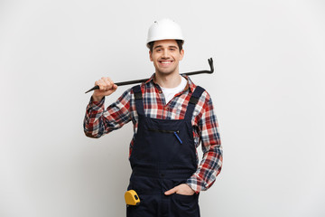 Smiling male builder in protective helmet holding crowbar