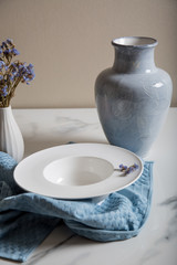 Empty dish plate ready for serving with jug and little flowers on marble background
