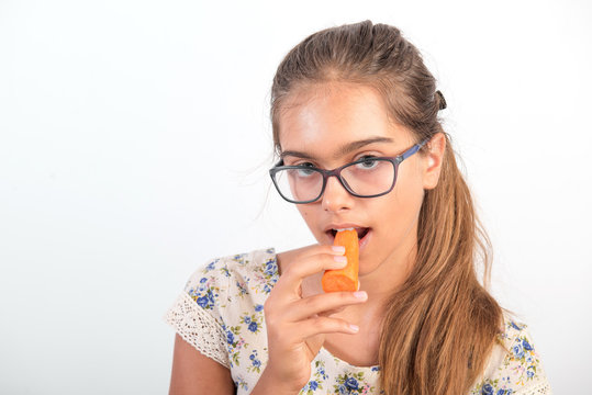 beautiful girl with carrot. Vitamins for teenagers. Vegetabl for healthy eating of children. Positive weight loss.  girl with glasses. girl bites a carrot. Natural vitamins to improve vision. 

