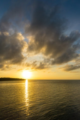USA, Florida, Orange sunset reflecting in silent ocean water with some clouds