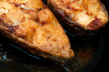 Fried fish snacks on frying pan. Pieces of fried fish in boiling oil.