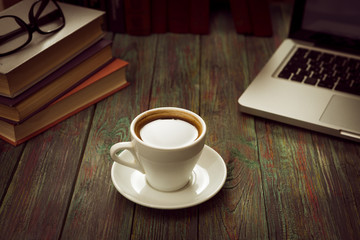 A cup of coffee in the workplace on a wooden table. A cup of coffee in the workplace on a wooden table. The concept of working outside the office