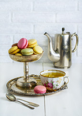 Multicolored macaroons in a metal vintage bowl on a white table