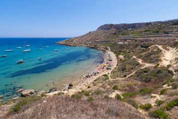Fototapeta na wymiar Beautiful azure blue water of Selmun beach in the summer time, in Maltese Imgiebah Bay, Il-Mellieha, Malta, June 2017