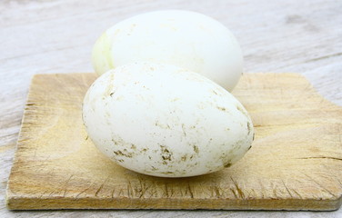Fototapeta na wymiar œufs de canne,sur planche en bois 