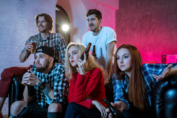 Friends watching a football match and drinking beer.