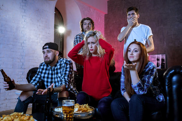 Friends watching a football match and drinking beer.