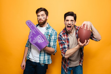 Portrait of a two cheerful young men holding rugby ball