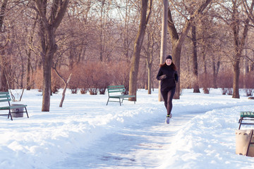 young woman athlete in black sport suit run in winter park
