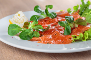 salted salmon with a slice of lemon on a sheet of green salad