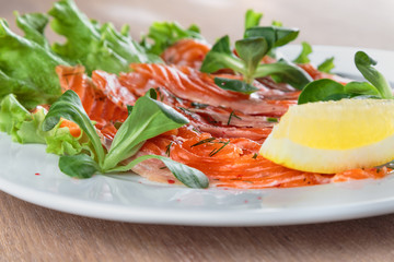 salted salmon with a slice of lemon on a sheet of green salad