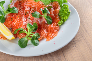 salted salmon with a slice of lemon on a sheet of green salad