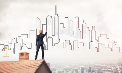 Man architect draw silhouette of modern city on blue sky. Mixed 