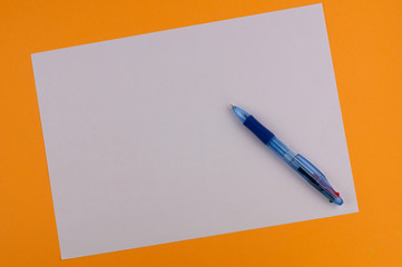 One multi color blue transparent ballpoint and white blank rectangle paper on background of orange paper with copy space