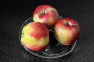 Apples on a glass plate on a dark background