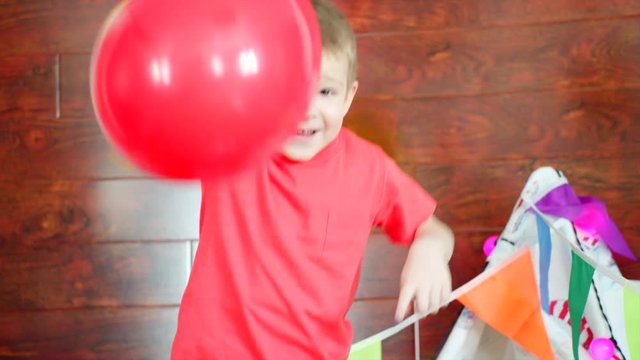 Little boy is playing with colorful ballons in the playroom