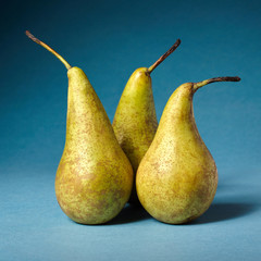 Three yellow pears on a dark blue paper background.