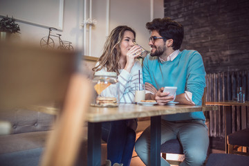  Beautiful loving couple sitting in a cafe drinking coffee and using phone. Love and romance concept.