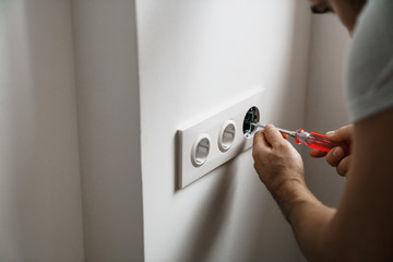 repair electricity socket man with bare hands. Incorrect safety or repair of the electrical outlet.