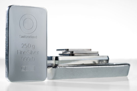 Minted silver bar weighing 250 grams against a background of a stack of various silver ingots. Selective focus..