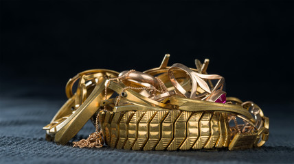 A scrap of gold. Old and broken jewellery, watches of gold and gold-plated on a dark background.