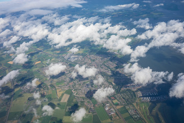 Farms in Holland, Netherlands with canal viewed from plane in sky with clouds