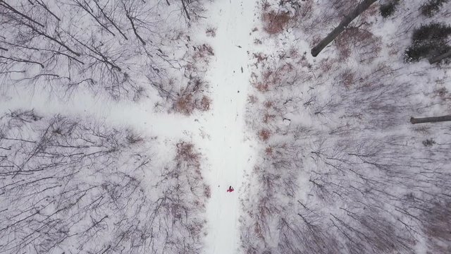 Man running on white winter forest road, top view drone aerial footage with runner moving from bottom to top. Inspiring fitness and motivation concept. Gimbal stabilized footage. Shot 4K with DLOG.