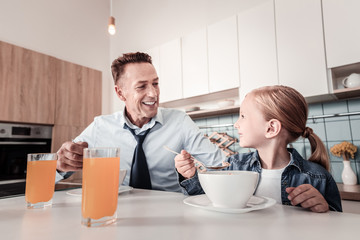 Lets talk. Joyful girl sitting near her father and turning head while being in all ears