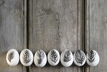 Easter white eggs decorated with feather isolated on grey rustic background