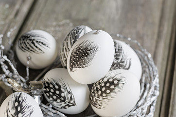 Easter white eggs decorated with feather in nest on rustic background