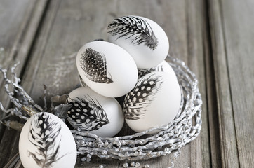 Easter white eggs decorated with feather in nest on rustic background