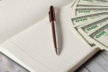 Notepad, pen and money on a light wooden background