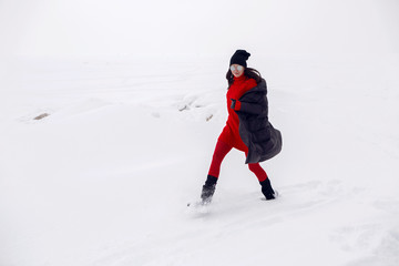 Fototapeta na wymiar girl running in a snowy field in a jacket and sunglasses