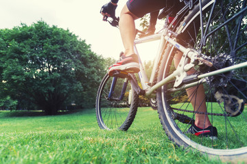 Obraz premium Cycling in park concept. Closeup of bicycle on green field at park in sunset. Picture for add text message. Backdrop for design art work.
