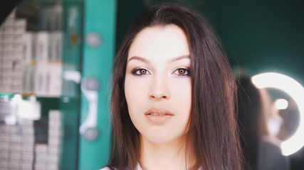 Young brunette in a beauty salon posing and looking into camera