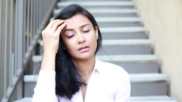 Closeup portrait, sad young woman in pink shirt sitting on stairs, really depressed, down about something, isolated outdoors stairs background. Negative emotion facial expression feeling reaction