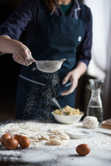 Image of hard working male cook or baker with dark skin wears apron, sheets well made dough, going to bake tart, isolated over black chalk background. Unrecognizable African American chef on kitchen