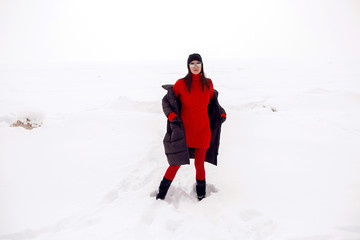 Fototapeta na wymiar girl running in a snowy field in a jacket and sunglasses
