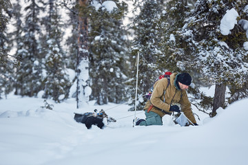 Take the challenge. Young man is seeking shelter in forest covered by snow, in the north of Sweden