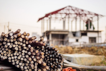 steel rebar for reinforcement concrete at construction site with house under construction background