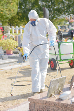 Man spraying chemical weed killer in cemetery