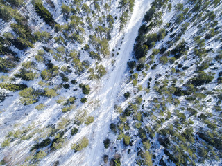 Aerial drone view of a winter road landscape. Snow covered forest and road from the top. Sunrise in  nature from a birds eye view. Aerial photography. Aerial photo. Quadcopter. Winter road
