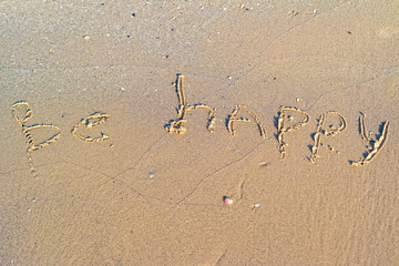 Be happy written in the sand.