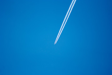 Airplanes leaving diagonal trace on a clear blue sky.