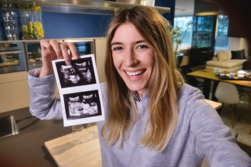 A woman videochat with her tablet the husband and announces the birth of the child and then that is pregnant showing him the ultrasound. Concept of birth, life and family.