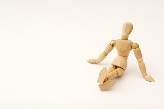 A wooden person sits on the floor, his legs are crossed, head slightly throwned back
