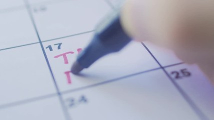 Close up of hand writing word Tax Day on calendar list
