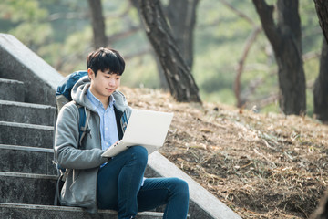 Asian man backpacking using laptop