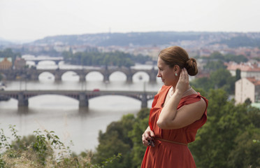 Young woman in orange dress enjoin view of Prague