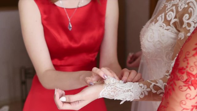 Bridesmaid helps the bride to wear dress